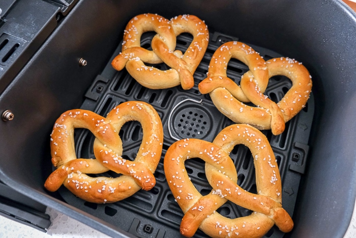 frozen soft pretzels in black air fryer tray on counter