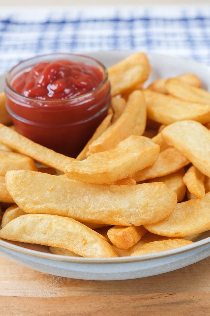 crispy steak fries in a bowl with ketchup behind