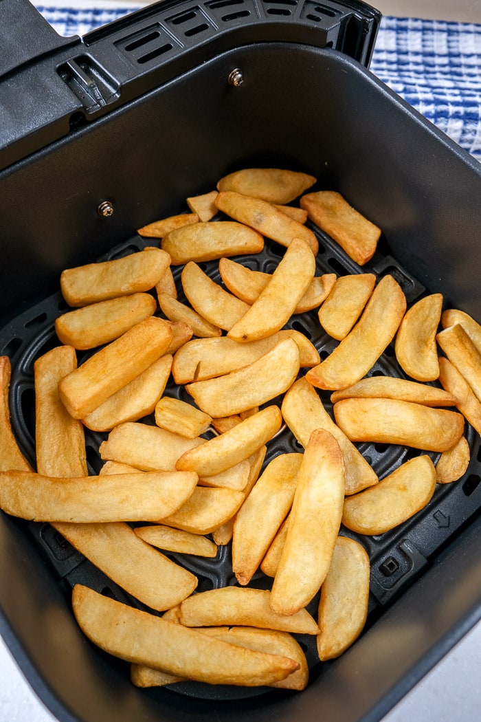 crispy steak fries in black air fryer tray with blue cloth behind
