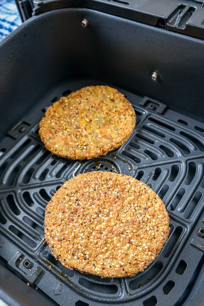 cooked veggie burgers in black air fryer tray