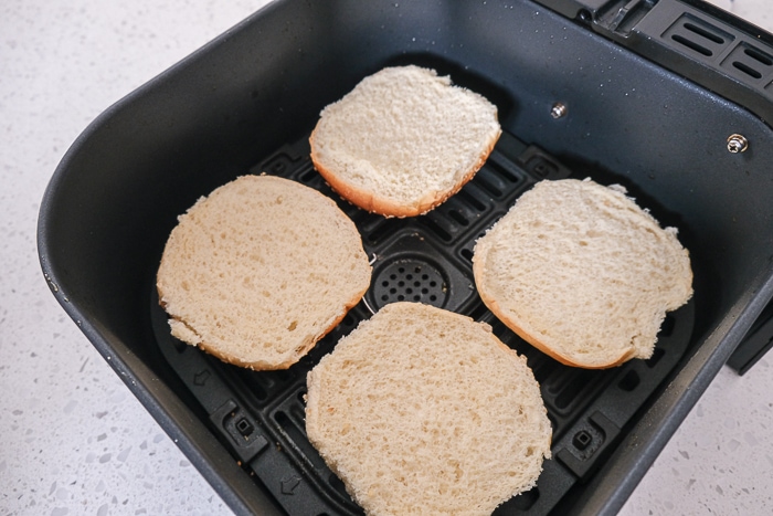 burger buns opened and laying in black air fryer tray
