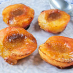 grilled half peaches on floral plate with spoon beside