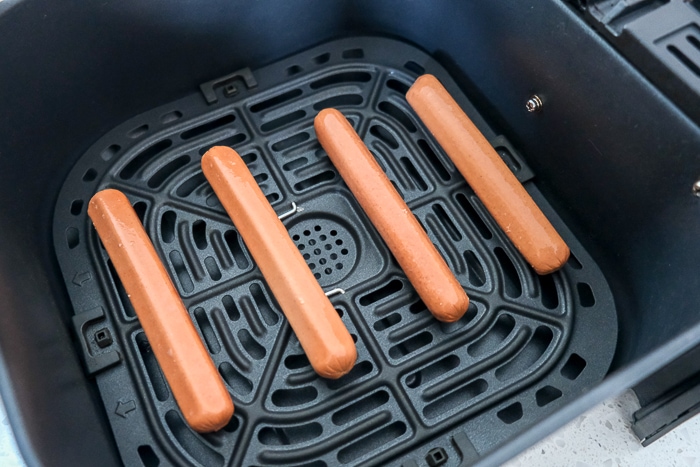 raw hot dogs in black air fryer tray