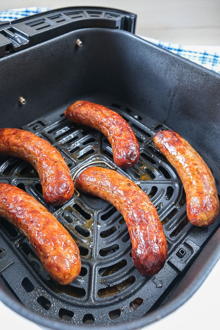 cooked italian sausages sitting in black air fryer tray