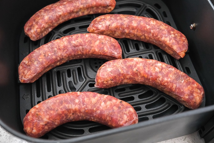 raw italian sausages in black air fryer tray