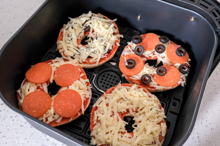 raw pizza bagels in black air fryer tray
