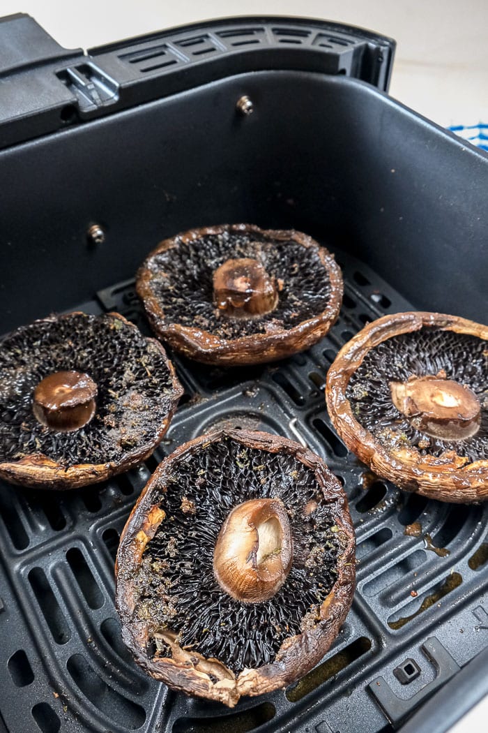 cooked portobello mushrooms in black air fryer tray