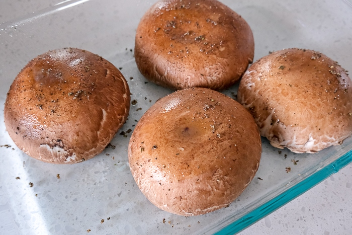 portobello mushrooms in glass baking dish covered in spices on white counter