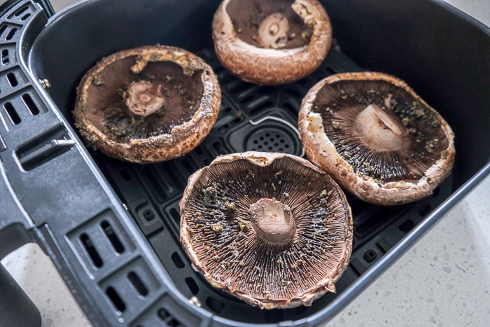 raw portobello mushrooms in black air fryer tray on counter