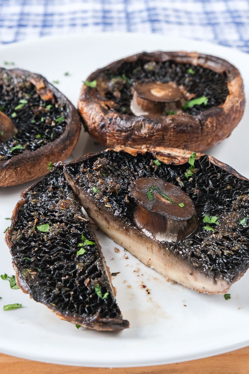 grilled portobello mushrooms on white plate with blue cloth behind