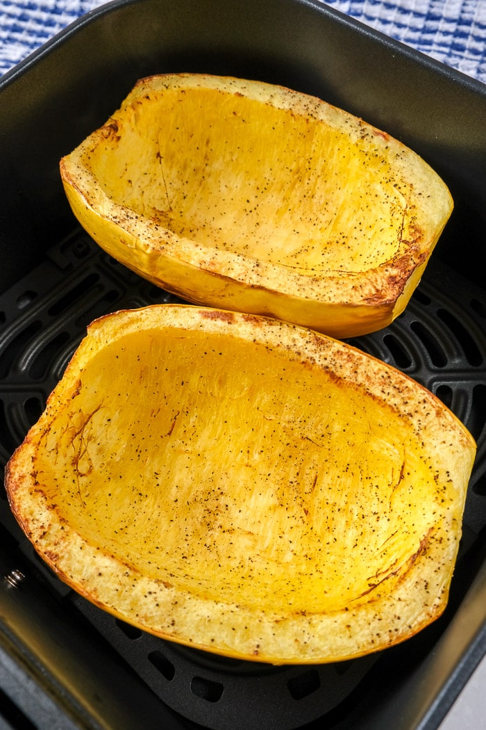 cooked spaghetti squash halves in black air fryer tray