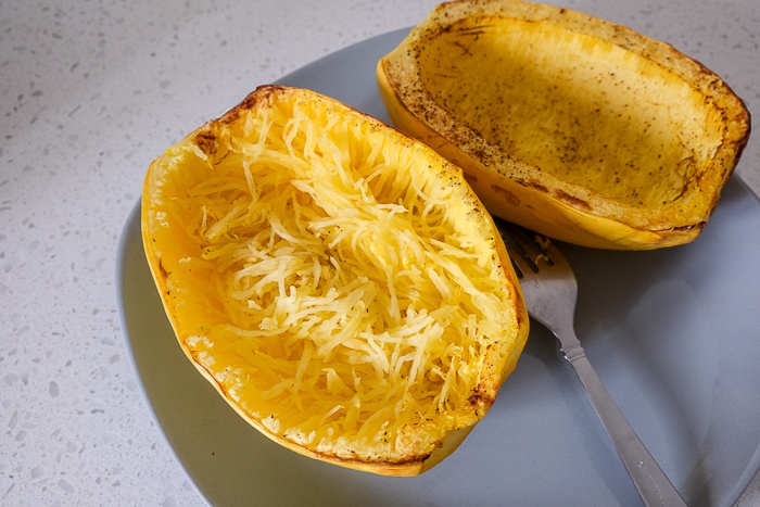 cooked spaghetti squash halves on plate with insides fluffed