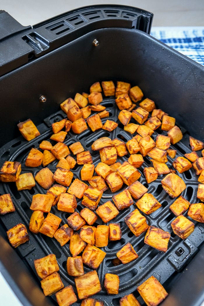 cooked pieces of sweet potato in black air fryer tray on counter
