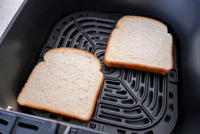 untoasted white bread in black air fryer tray