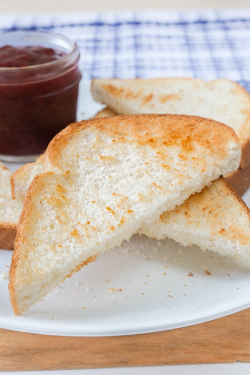 crispy toast pieces on white plate with jam behind