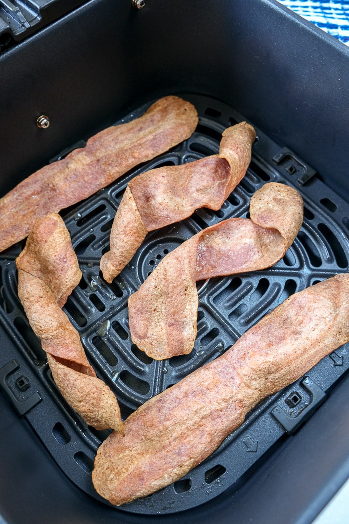 cooked turkey bacon in black air fryer tray on counter