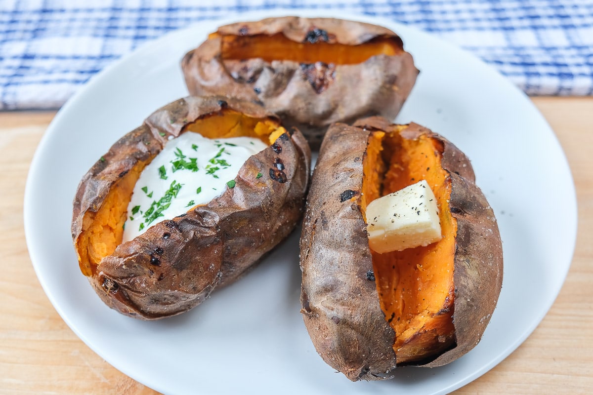 baked sweet potatoes on white plate with wooden underneath