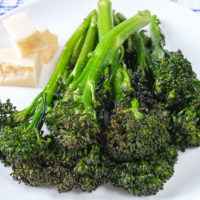 green broccolini on white plate on wooden board