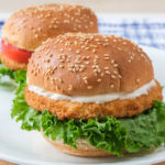 breaded chicken patties on buns with lettuce on white plate