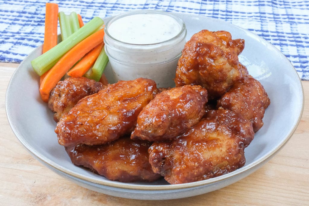 saucy chicken wings in bowl with ranch dipping sauce