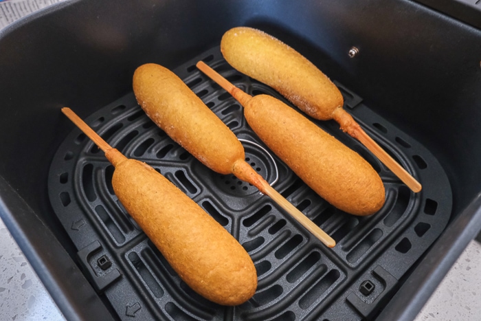 frozen corn dogs in black air fryer tray on counter
