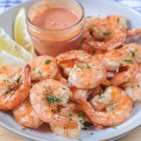 cooked shrimp in bowl with cocktail sauce and lemon slices