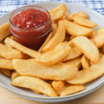bowl full of steak cut fries with dipping bowl of ketchup beside
