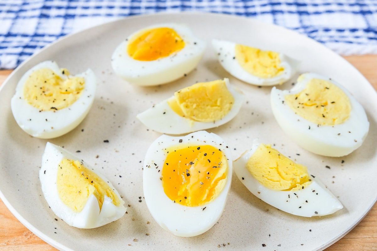 hard boiled eggs with pepper on plate on wooden board