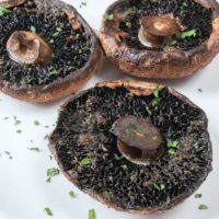 cooked portobello mushrooms on white plate with chopped parsley around