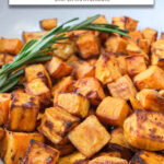 cooked sweet potato cubes in bowl with tig of rosemary and text overlay 