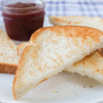 piece of toast on white plate with jam behind