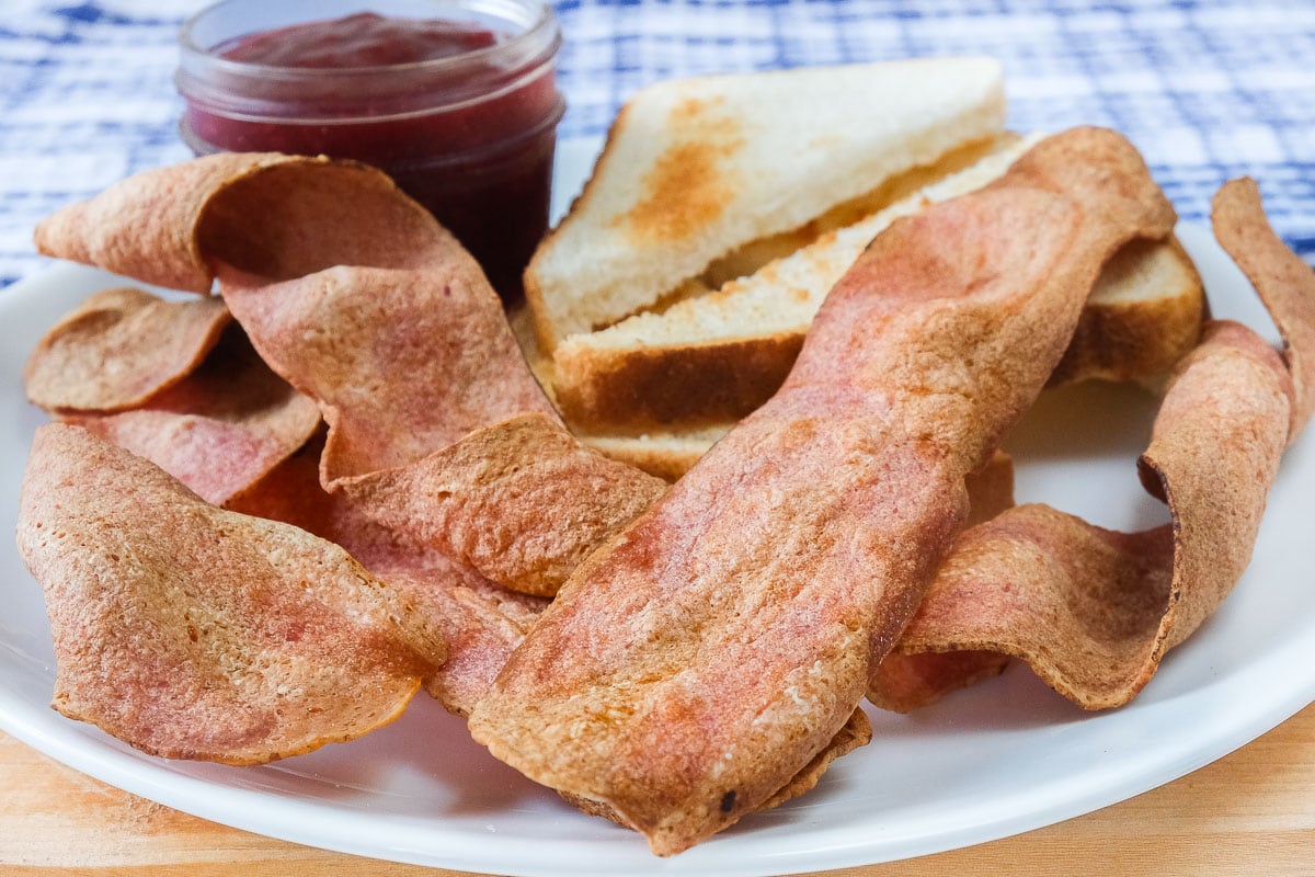 crispy turkey bacon on white plate with toast and jam behind