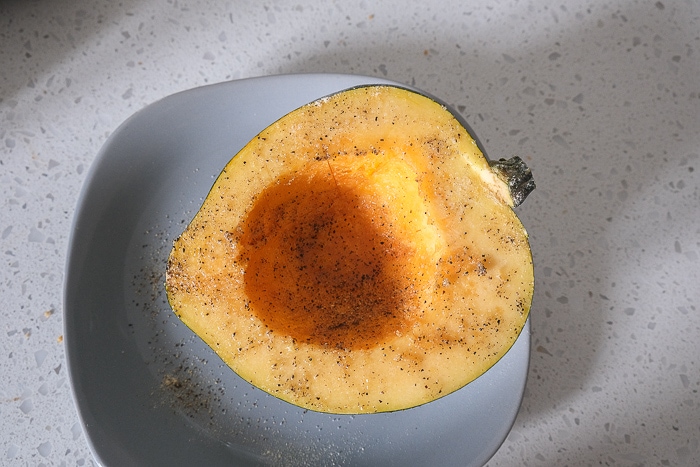 half of acorn squash on gray plate with spices inside