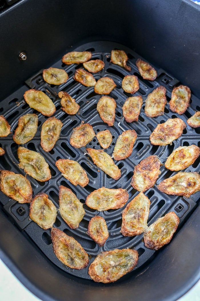 cooked banana chips in black air fryer tray on counter