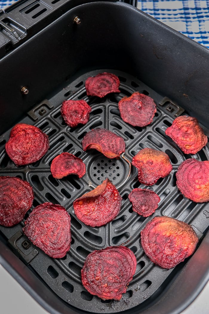 cooked beet chips in black air fryer tray on counter top