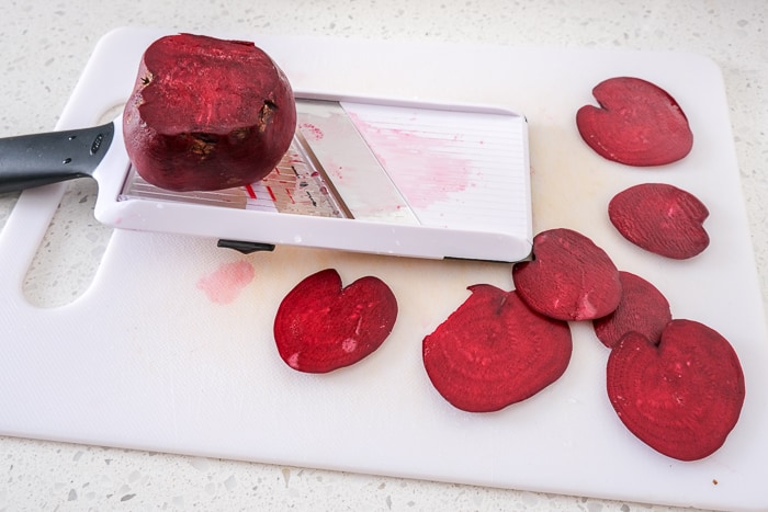 beet slices on white cutting board beside mandolin