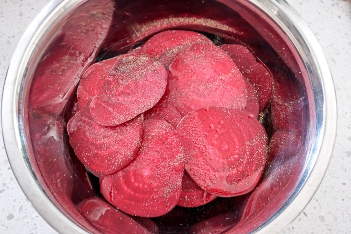 raw beet slices in silver mixing bowl on white counter