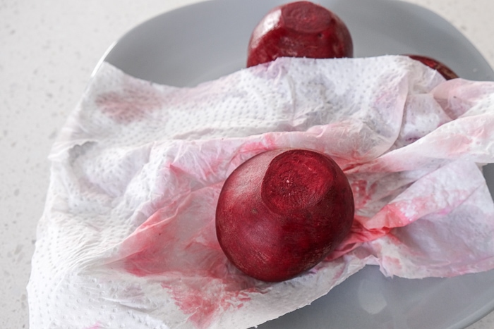 paper towel wiping off beets on small grey plate