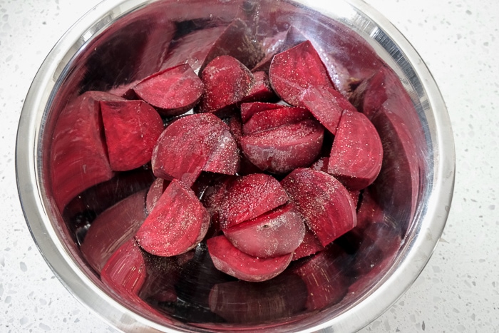 raw beets in silver mixing bowl with spices on top