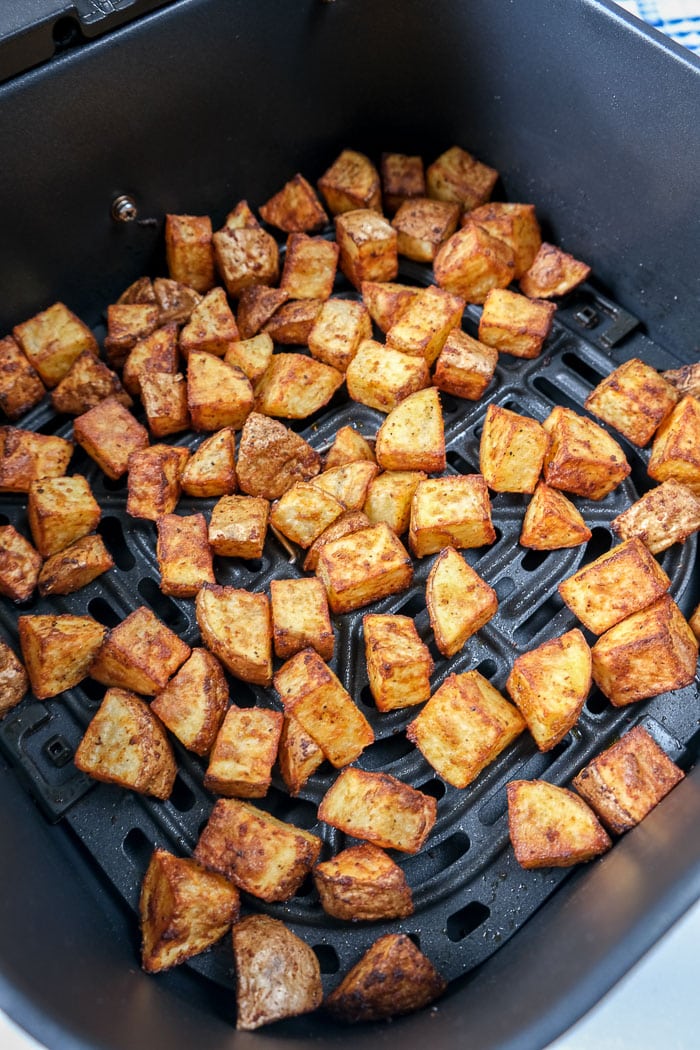 breakfast potatoes in black air fryer basket on counter top
