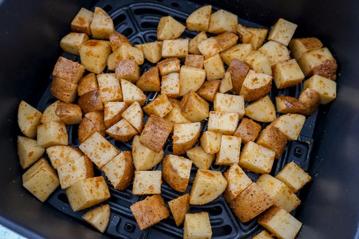 raw potatoes in black air fryer tray