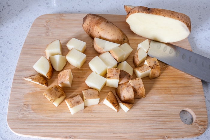 potatoes cut into cubes on wooden cutting board on counter