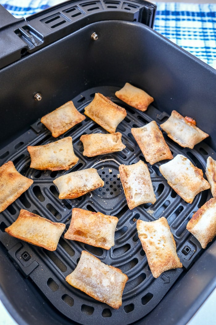 cooked pizza bites in black air fryer tray on counter