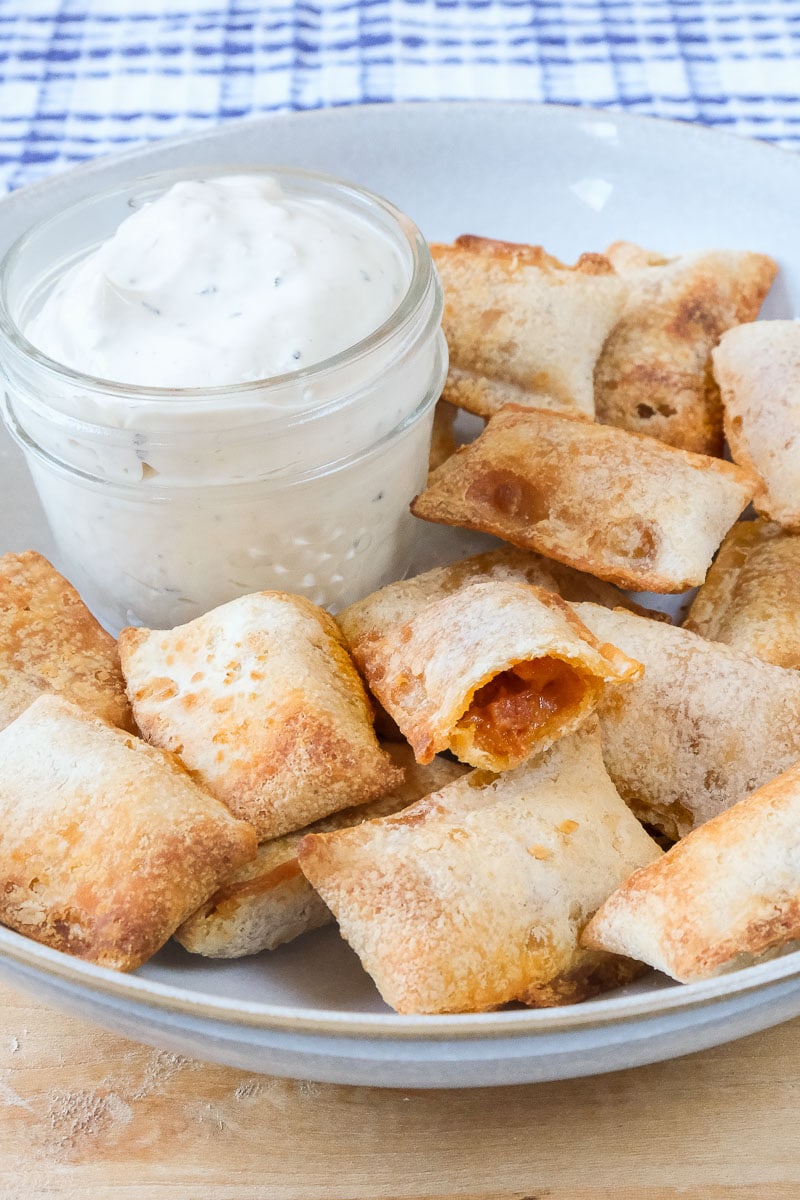 cooked pizza bites in bowl with ranch dipping sauce behind