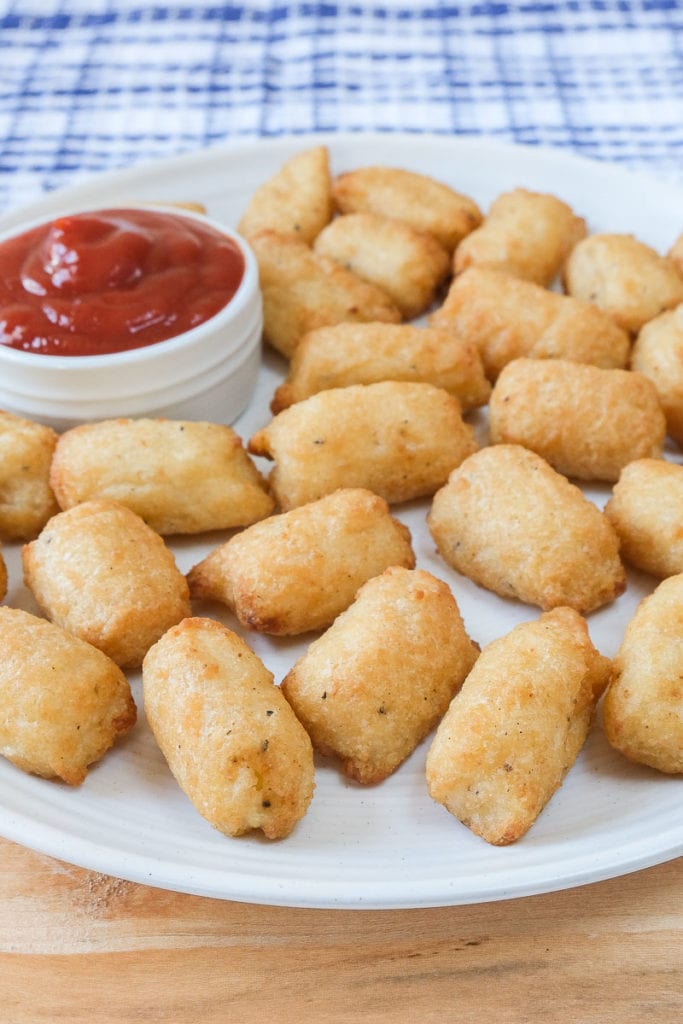 crispy veggie tots on white plate with dipping sauce beside