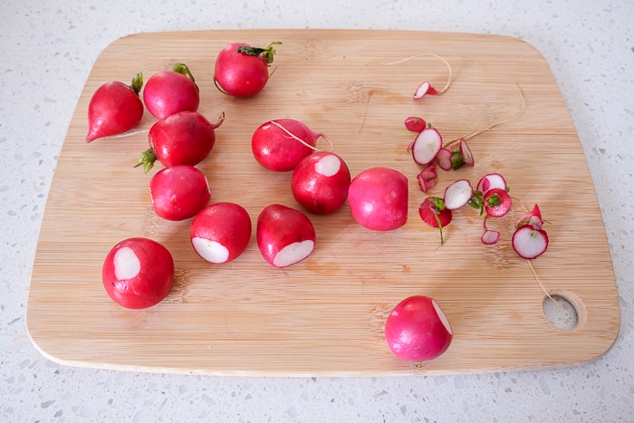 radishes on wooden cutting board with tops and bottoms cut off