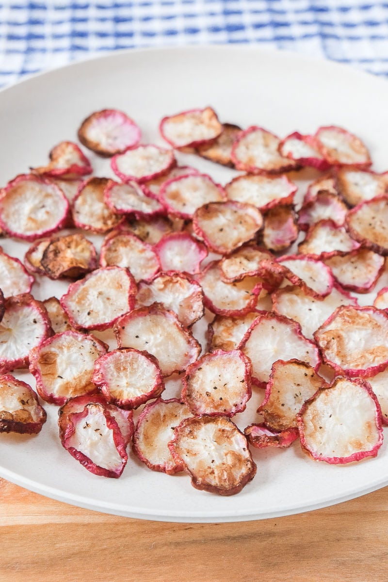 radish chips on white plate sitting on wooden cutting board