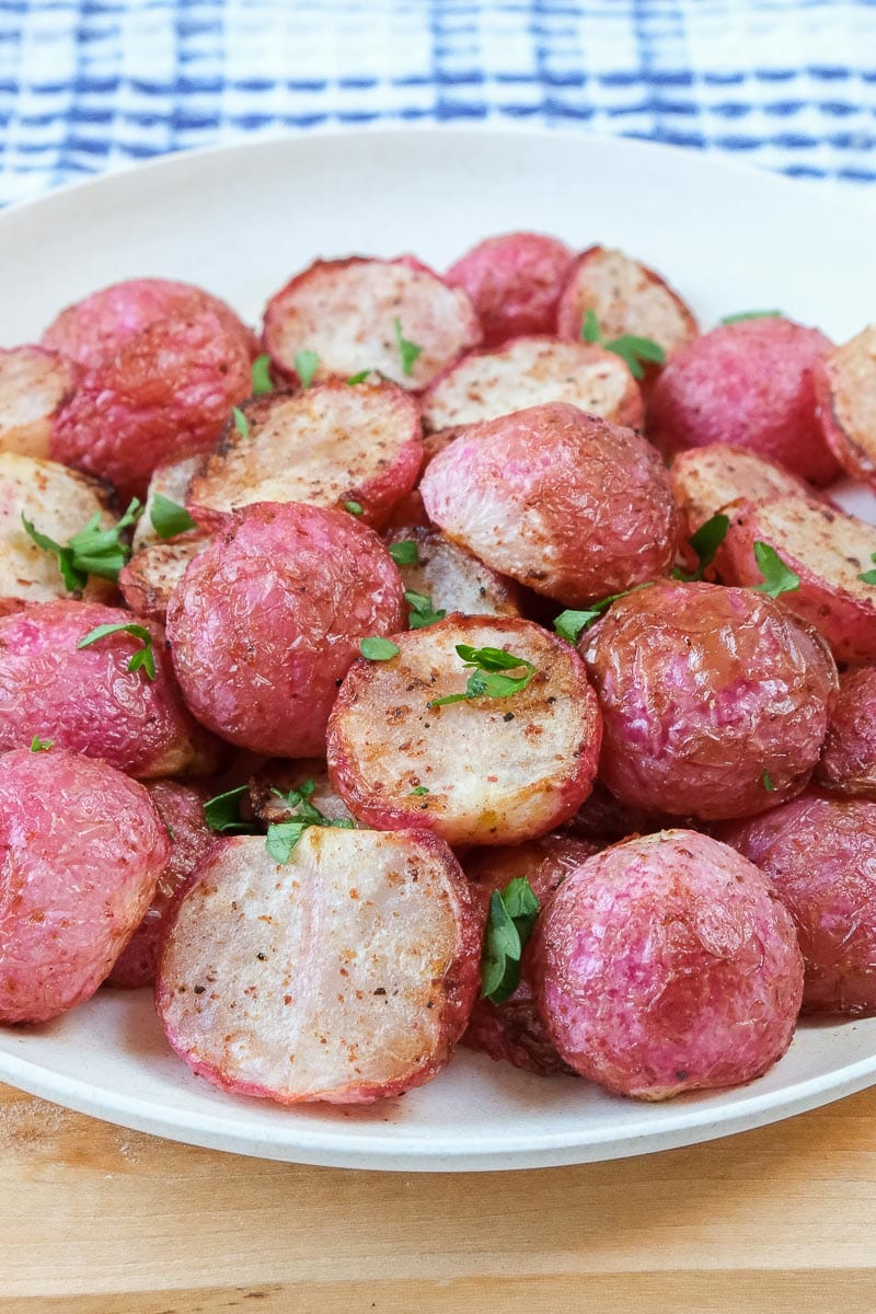 cooked radishes on white plate with chopped parsley