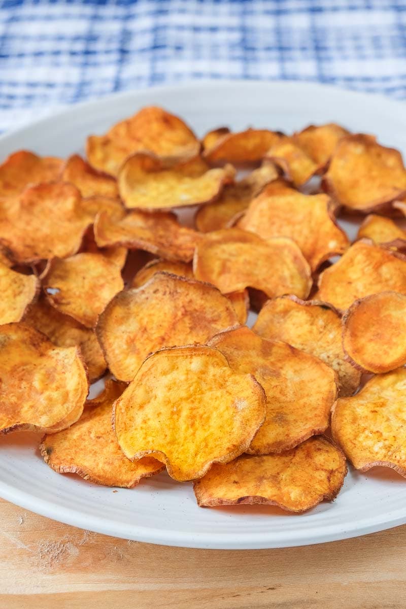 sweet potato chips on white plate with blue cloth behind