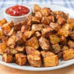 white plate of potatoes with ketchup for dipping